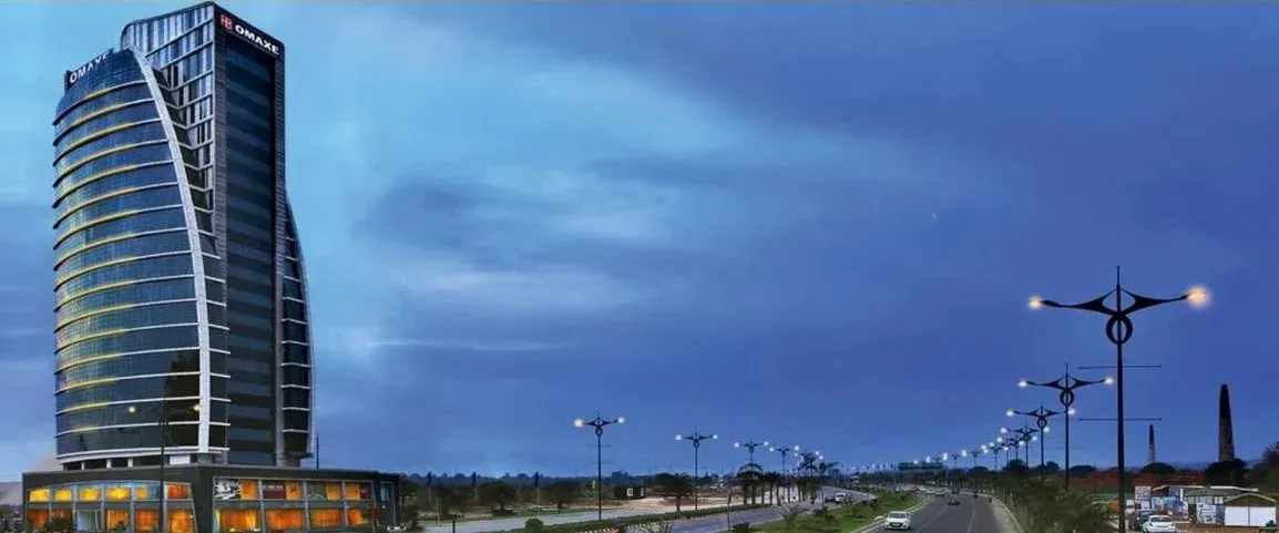 Omaxe tower at dusk beside a lit road